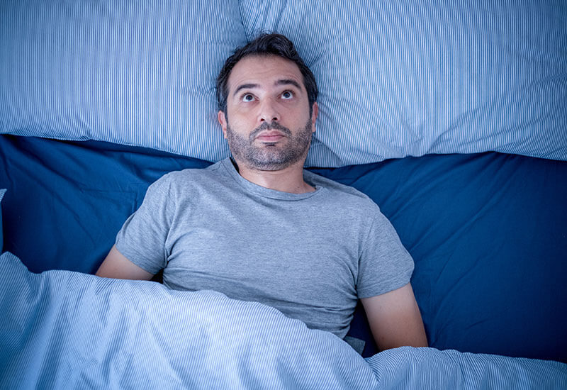 A man awake in bed, highlighting sleep disorders in Dallas, TX