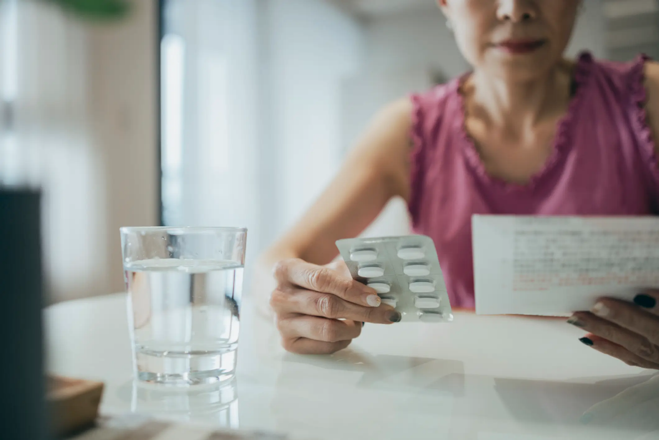 Women reading the prescription and holding medicine in the other hand
