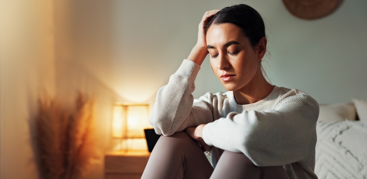 Women sitting indoors with a hand on their head feeling anxious