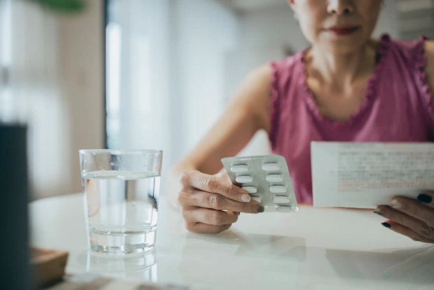 A Women reading the prescription and holding medicine in the other hand in Dallas, Texas